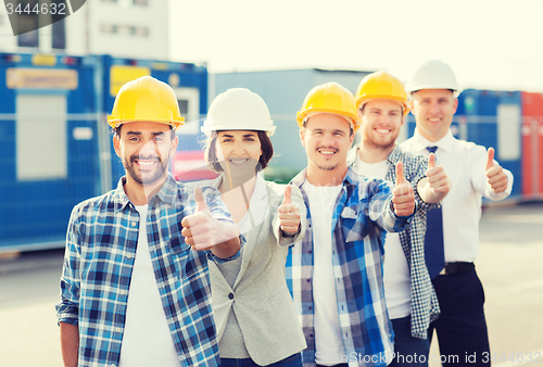 Image of group of smiling builders in hardhats outdoors