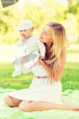 Image of happy mother with little baby sitting on blanket