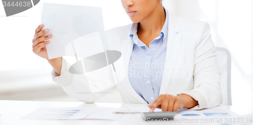 Image of businesswoman working with calculator in office