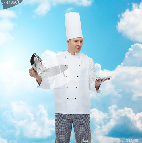 Image of happy male chef cook opening cloche