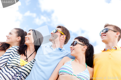 Image of group of happy friends hugging on beach