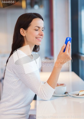 Image of smiling woman with smartphone and coffee at cafe