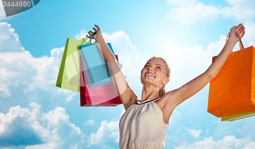 Image of smiling woman with shopping bag rising hands