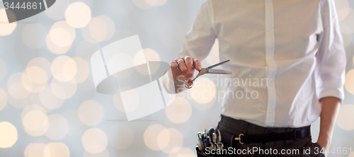 Image of close up of male stylist with scissors over lights