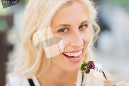 Image of happy woman eating dinner at restaurant terrace