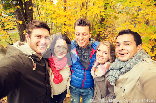 Image of group of smiling men and women in autumn park