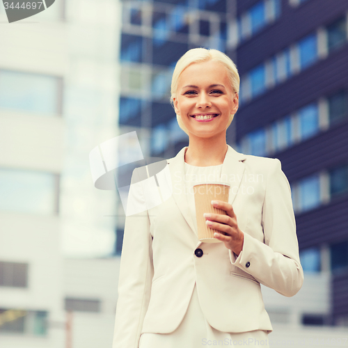 Image of smiling businesswoman with paper cup outdoors