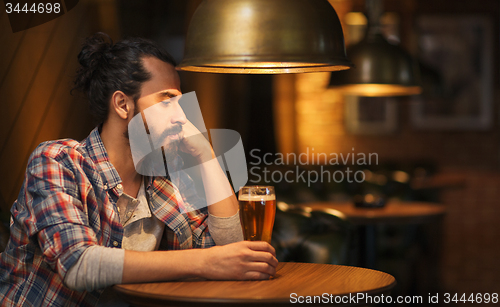 Image of unhappy lonely man drinking beer at bar or pub