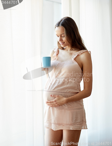 Image of happy pregnant woman with cup drinking tea at home