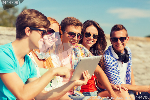 Image of group of smiling friends with tablet pc outdoors