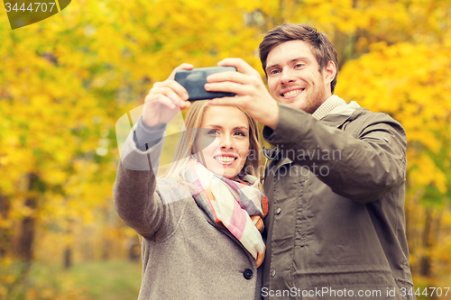Image of smiling couple hugging in autumn park