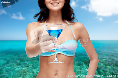 Image of happy young woman in swimsuit drinking cocktail