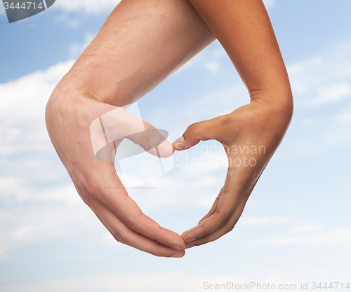 Image of woman and man hands showing heart shape