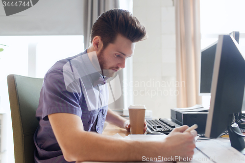 Image of creative male office worker with coffee writing