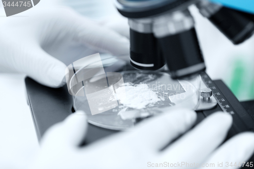 Image of close up of hand with microscope and powder sample
