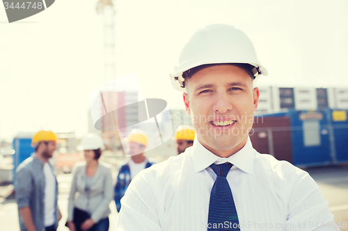 Image of group of smiling builders in hardhats outdoors