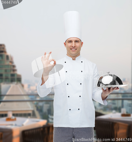 Image of happy male chef cook with cloche showing ok sign