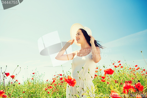 Image of smiling young woman in straw hat on poppy field