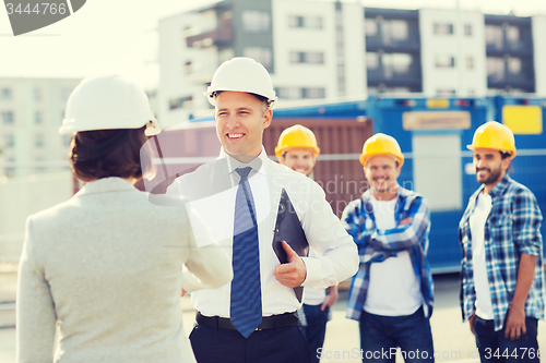 Image of group of smiling builders in hardhats outdoors