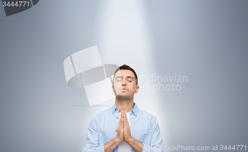Image of man praying under ray of ligh