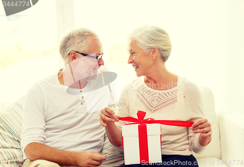 Image of happy senior couple with gift box at home