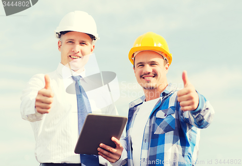 Image of smiling builders in hardhats with tablet pc