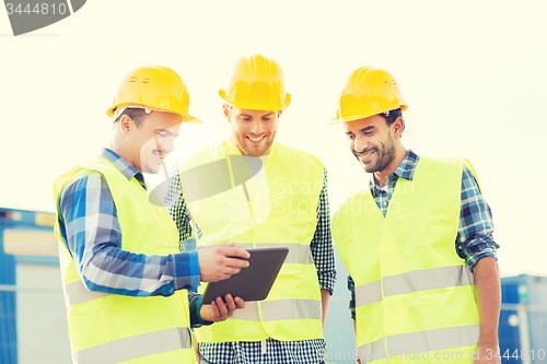 Image of smiling builders in hardhats with tablet pc