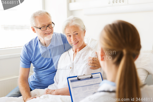 Image of senior woman and doctor with clipboard at hospital