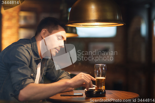 Image of man drinking beer and smoking cigarette at bar