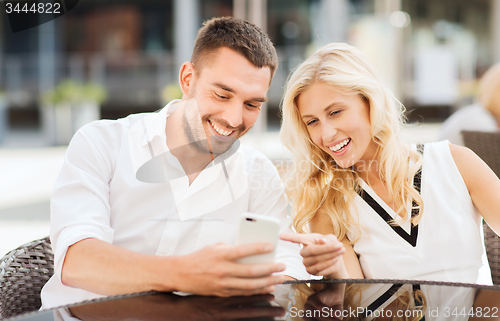Image of happy couple with smatphone at city street cafe