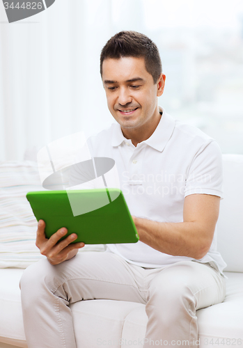 Image of smiling man working with tablet pc at home