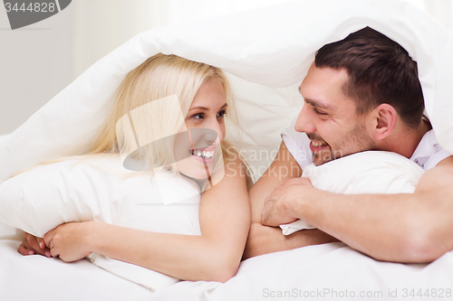 Image of happy couple lying in bed and talking at home