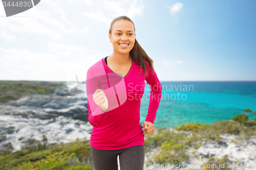 Image of smiling woman running on beach