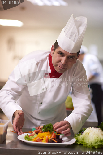 Image of chef in hotel kitchen preparing and decorating food