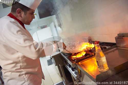 Image of chef in hotel kitchen prepare food with fire