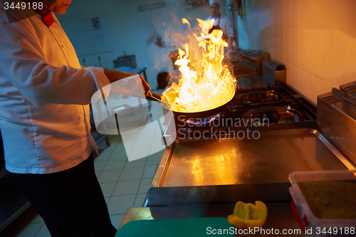 Image of chef in hotel kitchen prepare food with fire