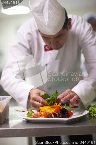 Image of chef in hotel kitchen preparing and decorating food