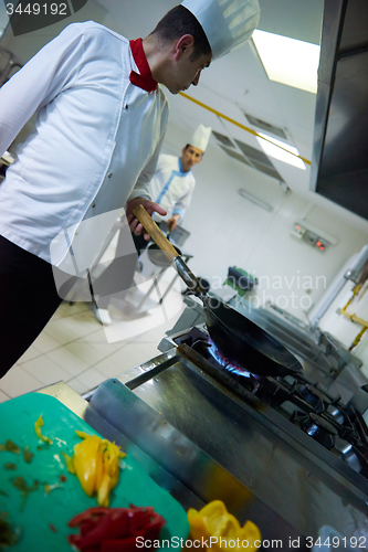 Image of chef in hotel kitchen prepare food with fire