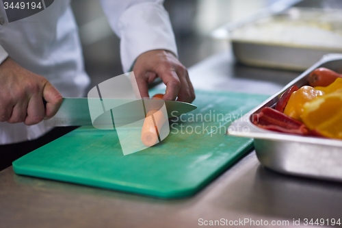 Image of chef in hotel kitchen  slice  vegetables with knife