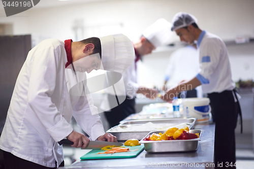 Image of chef in hotel kitchen  slice  vegetables with knife