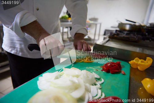 Image of chef in hotel kitchen  slice  vegetables with knife