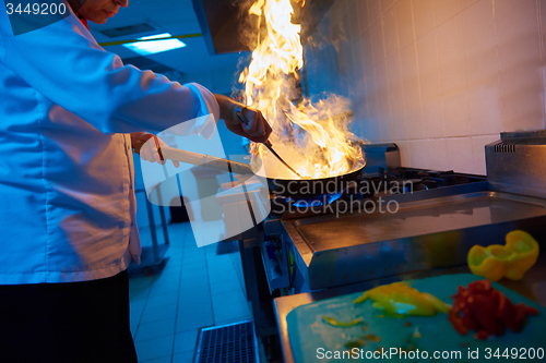 Image of chef in hotel kitchen prepare food with fire