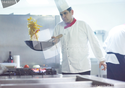 Image of chef in hotel kitchen prepare food with fire