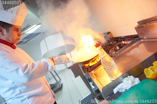 Image of chef in hotel kitchen prepare food with fire