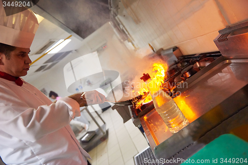 Image of chef in hotel kitchen prepare food with fire