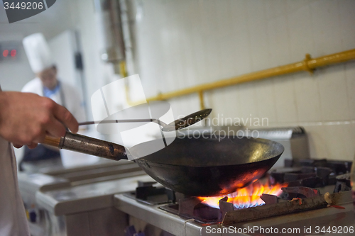 Image of chef in hotel kitchen prepare food with fire