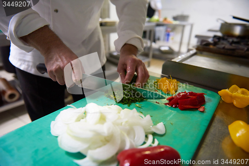 Image of chef in hotel kitchen  slice  vegetables with knife