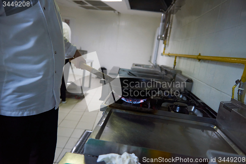 Image of chef in hotel kitchen prepare food with fire