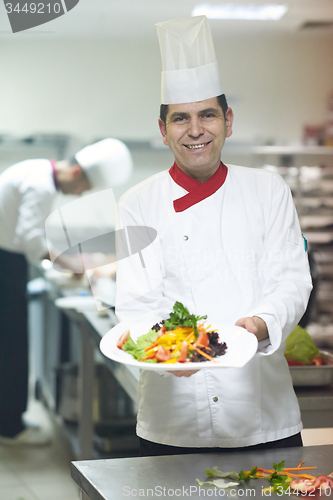 Image of chef in hotel kitchen preparing and decorating food