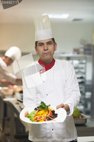 Image of chef in hotel kitchen preparing and decorating food